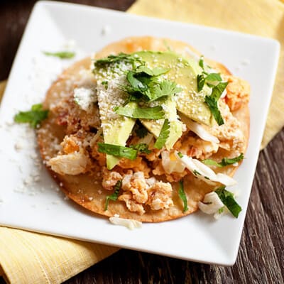 Overhead view of an open-faced tostada on a white plate.