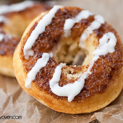 A close up of a cinnamon roll donut on wax paper.