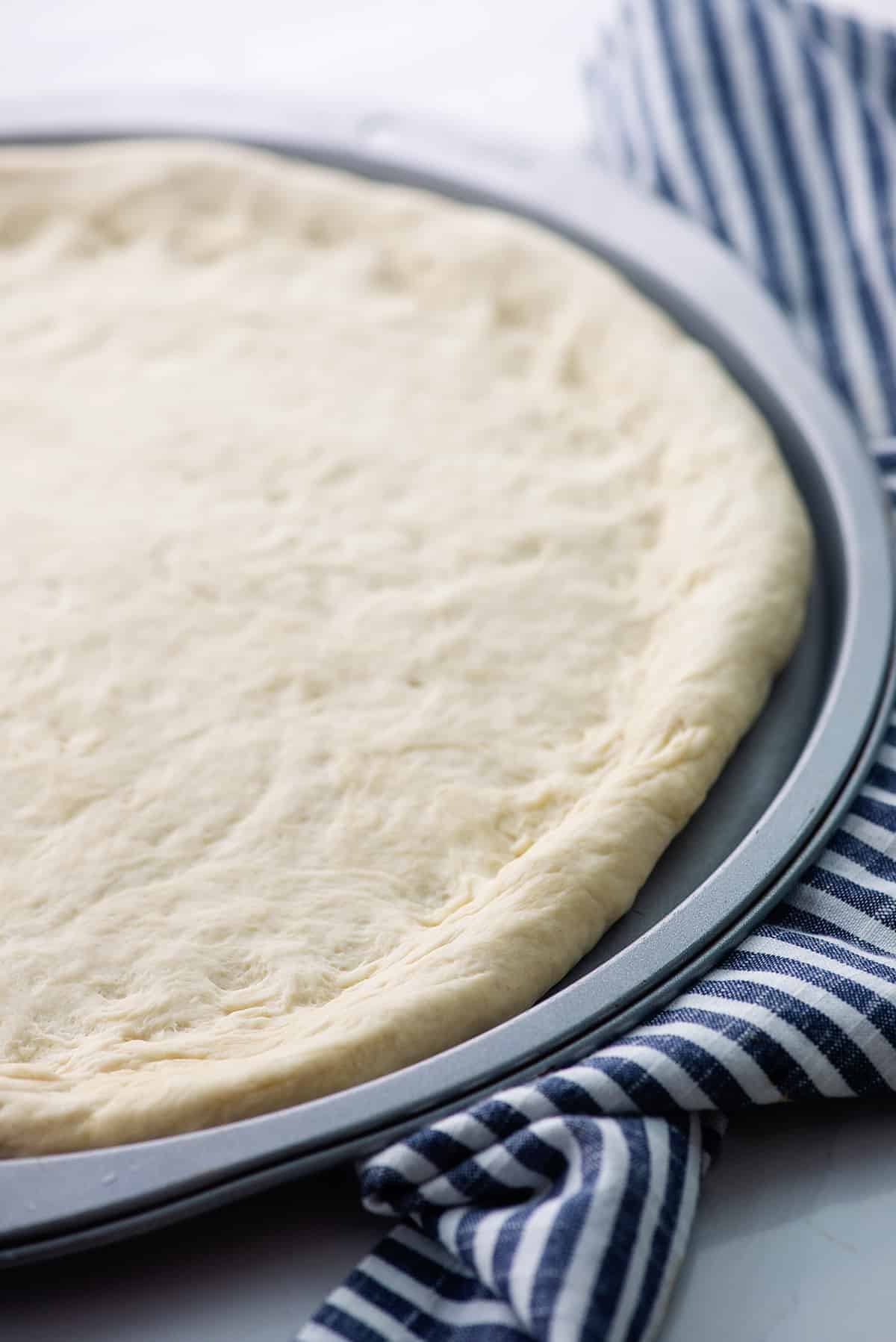 homemade pizza dough on pizza pan.