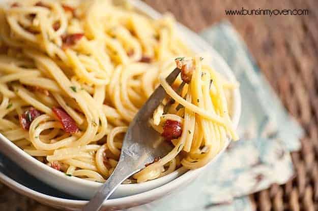 A bowl of spaghetti noodles with a fork twisted into some noodles.