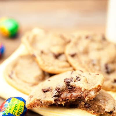 A stack of cookies on a plate surrounded by Cadbury creme eggs.