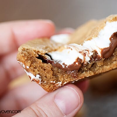 A person holding up a square peanut butter smores cookie cup.