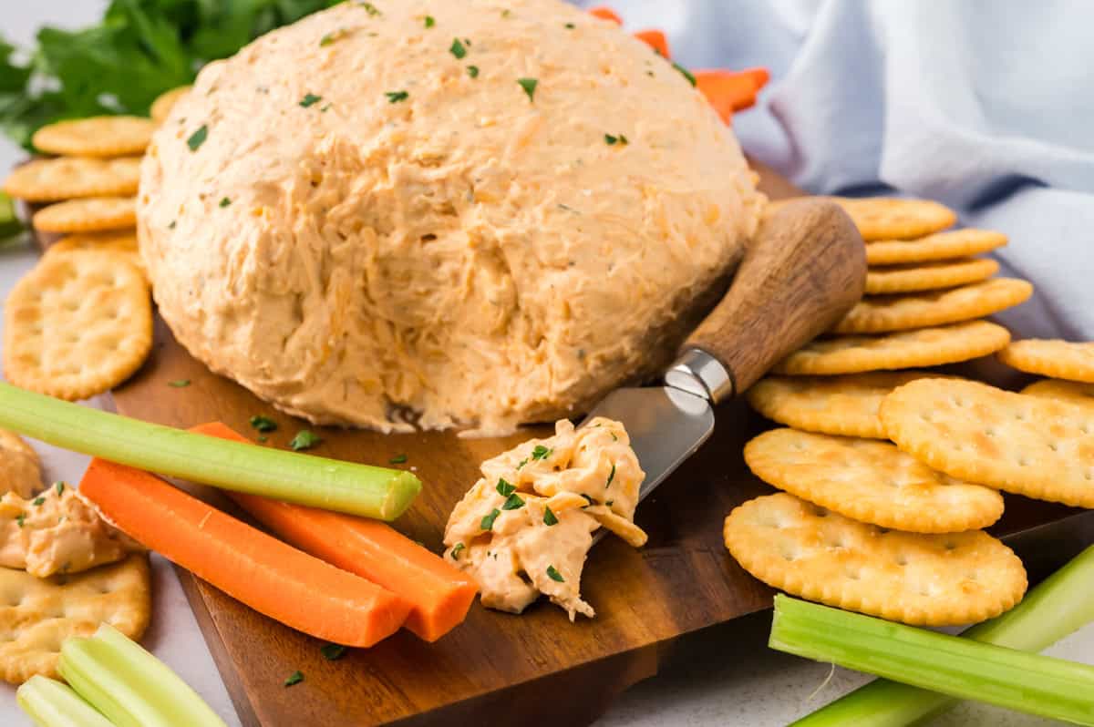 Crackers and a cheeseball on a square plate.