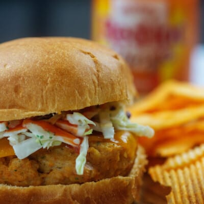 buffalo chicken burger with ranch coleslaw on cutting board by chips