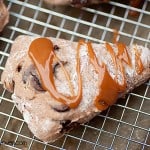 A close up of a caramel covered scone on a wire cooling rack.