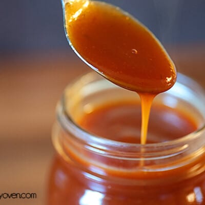 A jar of barbecue sauce with a spoon above it.