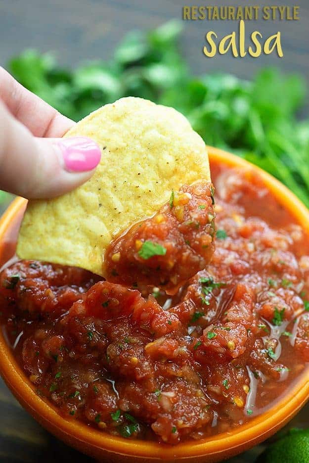 A woman dipping a tortilla into salsa,