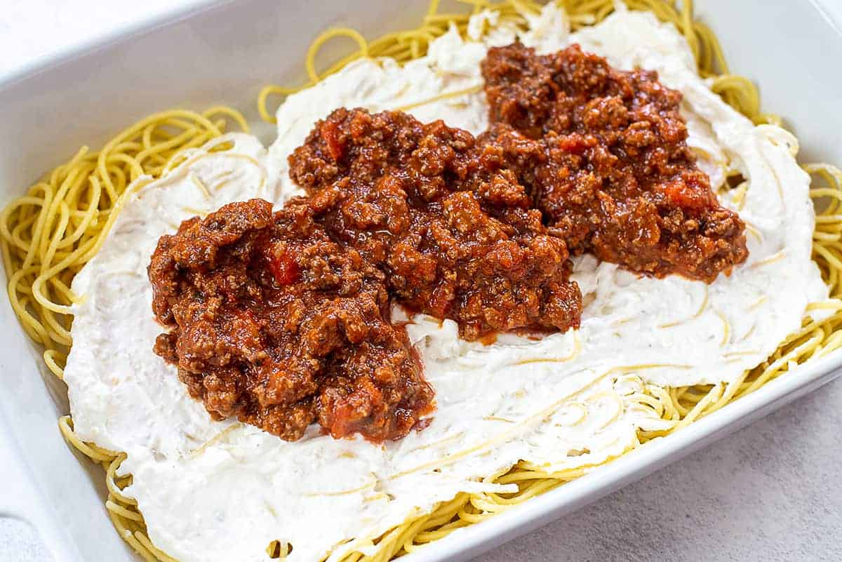 spaghetti, cream cheese, and pasta sauce layered in baking dish.