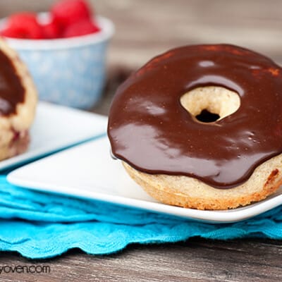 A close up of a chocolate frosted donut on a small square plate.