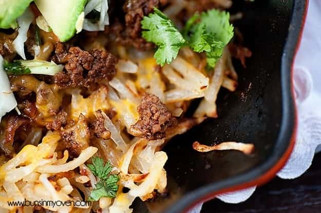 A close up of beef and cilantro in a cast iron skillet.