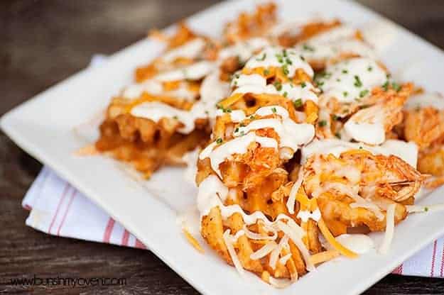 A closeup of buffalo chicken waffle fries on a Square white plate