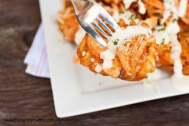A fork stabbed through buffalo chicken waffle fries 
