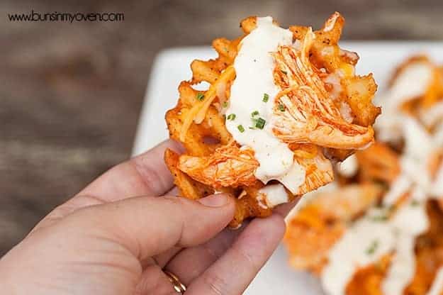 A person holding a waffle fry with ranch dressing on it