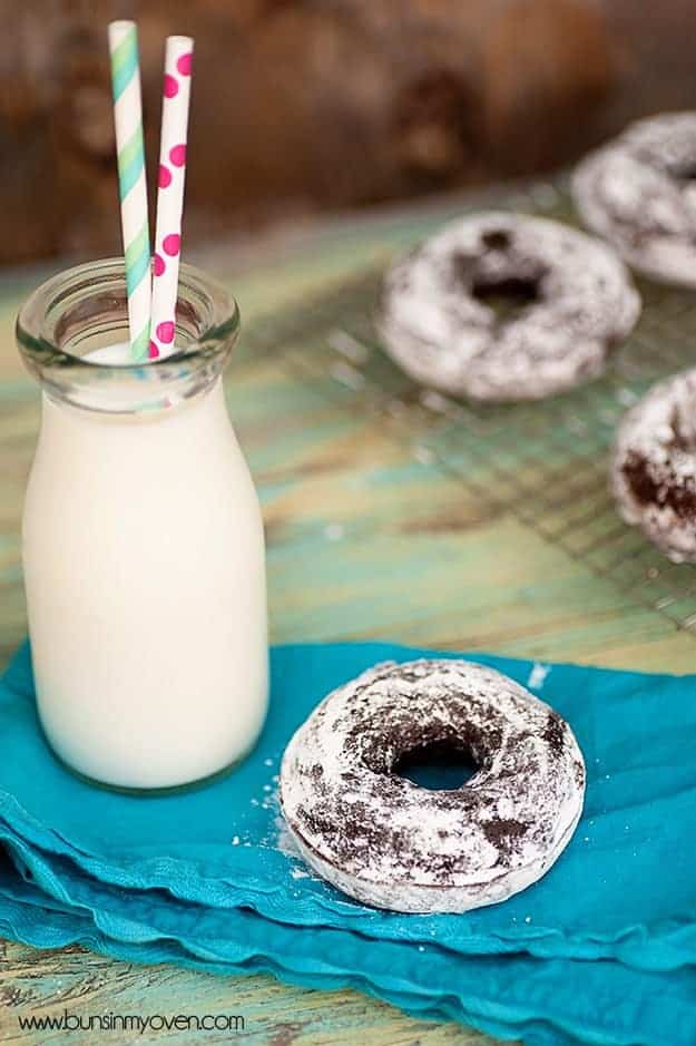 A doughnut on a cloth napkin next to a jar of milk 