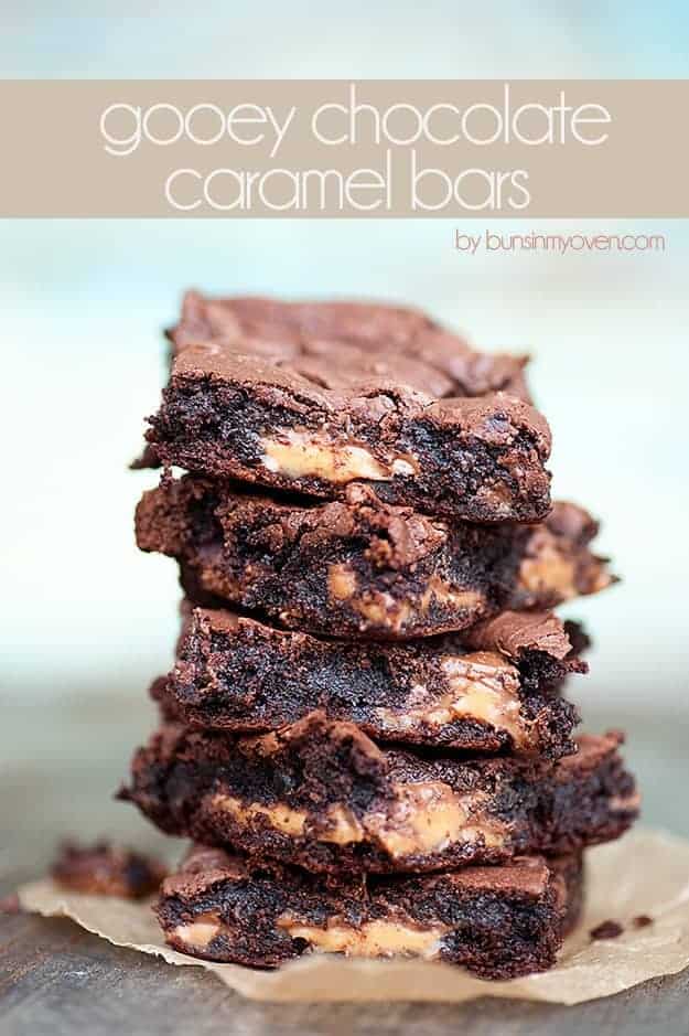 A closeup of several gooey chocolate caramel bars stacked up 