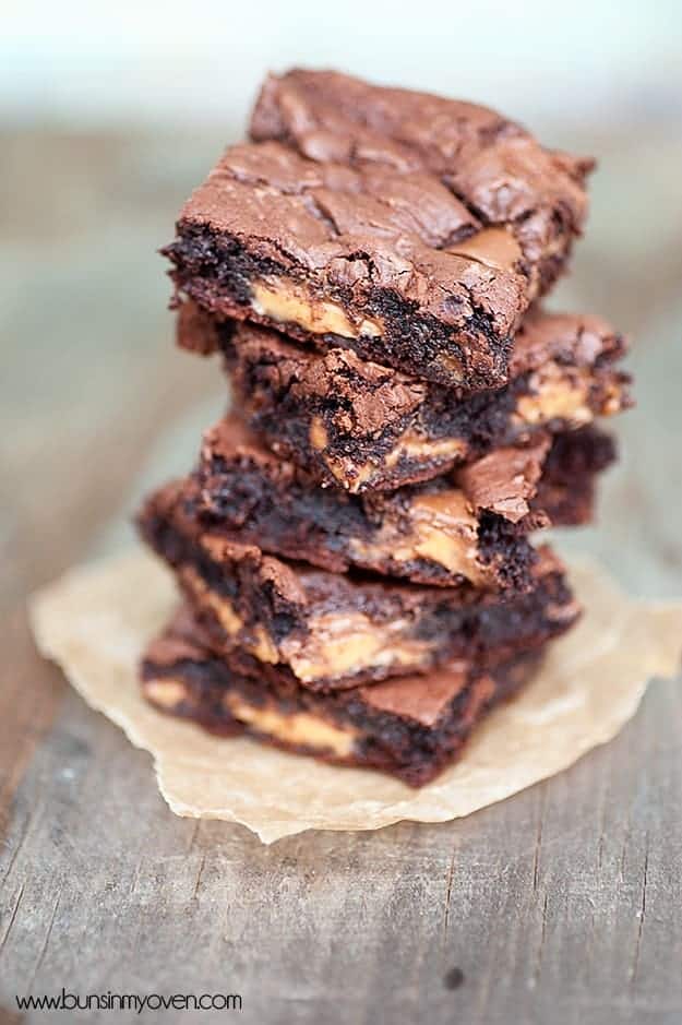 A stack of several gooey chocolate caramel bars on a napkin 