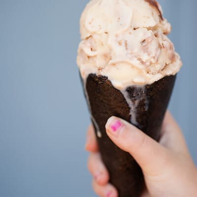 A closeup of a girl holding up an ice cream cone