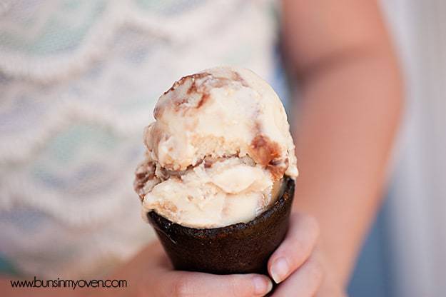 A closeup of a girl holding peanut butter ice cream in a cone up to the camera 