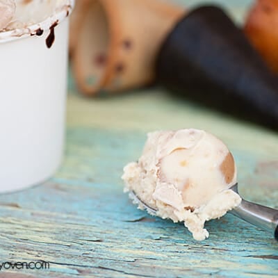 A closeup of an ice cream scoop next to a cup of ice cream