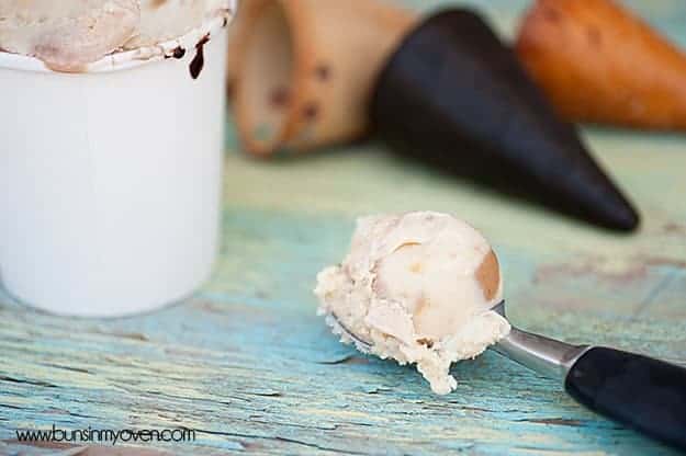 A closeup of an ice cream scoop next to a cup of ice cream 