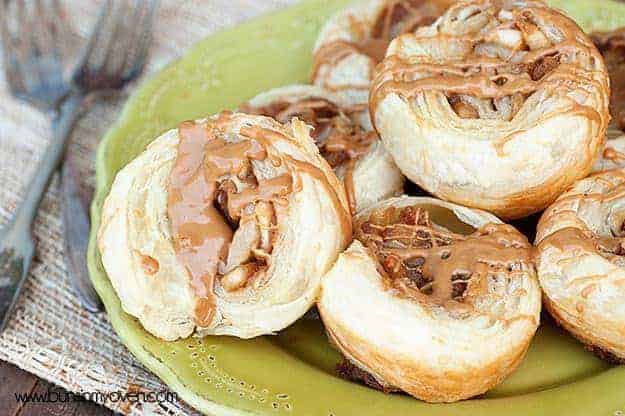 A close up of a pile of apple pinwheels with biscoff drizzled over the top.