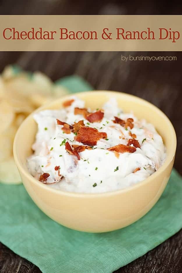 A close up of a bowl of ranch dip topped with bacon pieces.