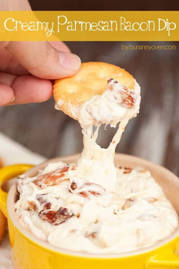 A ritz cracker being dipped into a parmesan cheese dip.