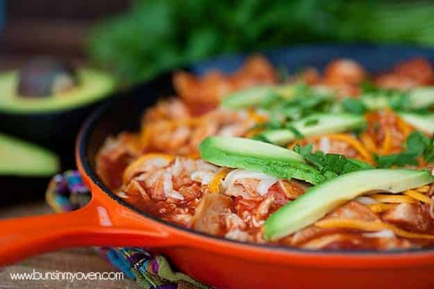 A cast-iron skillet with shredded chicken and avocado slices on a folded cloth napkin.