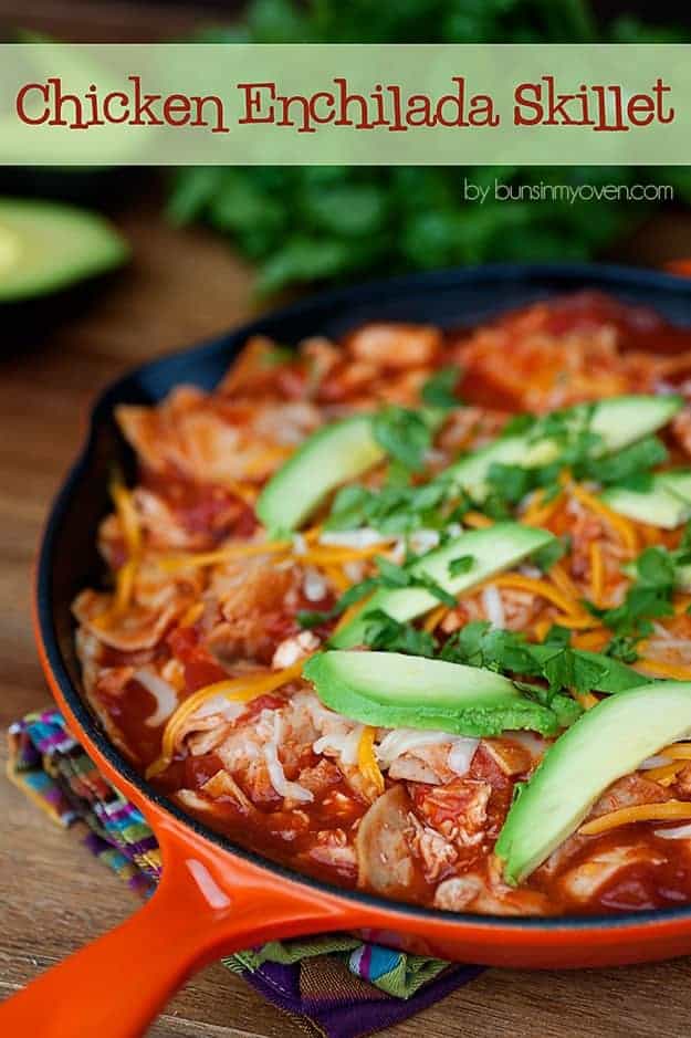 A cast-iron skillet full of chicken enchilada topped with avocado slices.