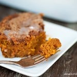 A fork with a bite of pumpkin coffee cake on it resting a white plate.