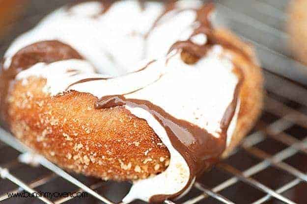 A close up of a cake donut topped with marshmallow and chocolate frosting.