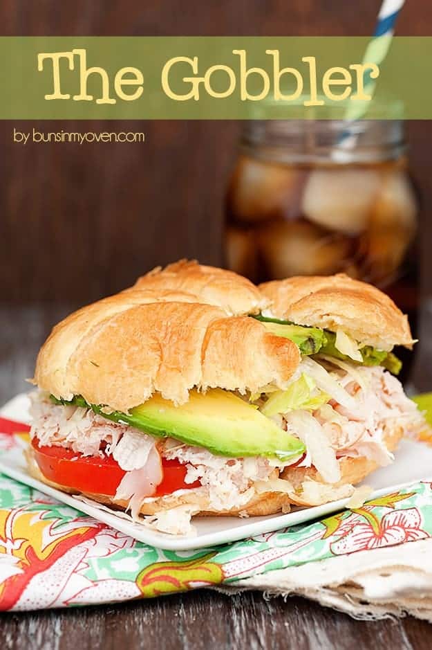 A close up of a turkey sandwich in front of a jar of iced tea