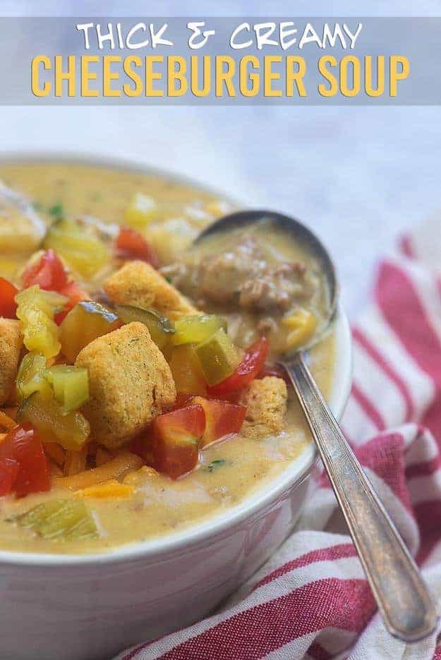 A bowl of soup topped with croutons and a spoon in the bowl.
