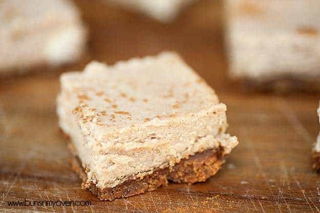 A biscoff crust cheesecake square up close on a wooden cutting board.