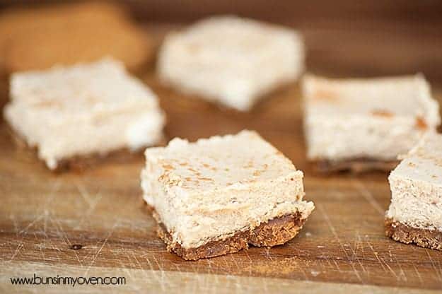 Several cheesecake squares on a wooden cutting board.