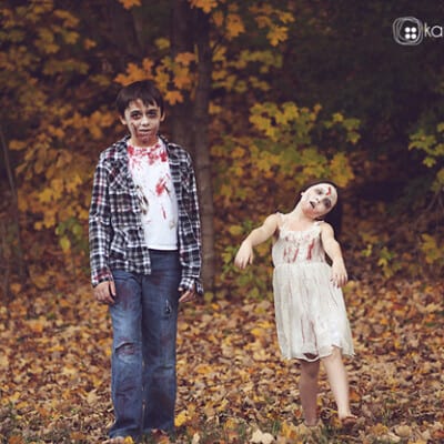 Two kids dressed as zombies in the woods.