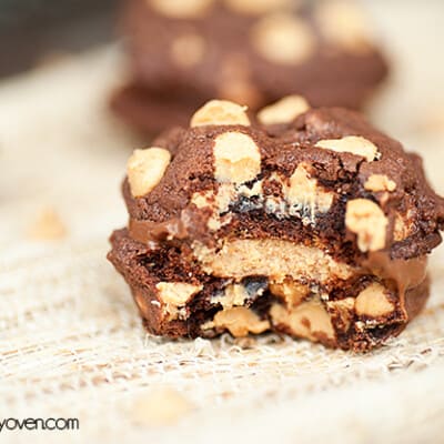 A close up of a chocolate peanut butter cookie with a bite taken out of it on a placemat.