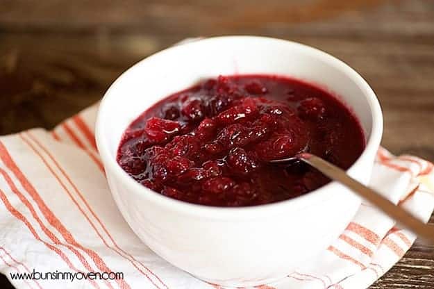 A bowl of cranberries on a striped cloth napkin.