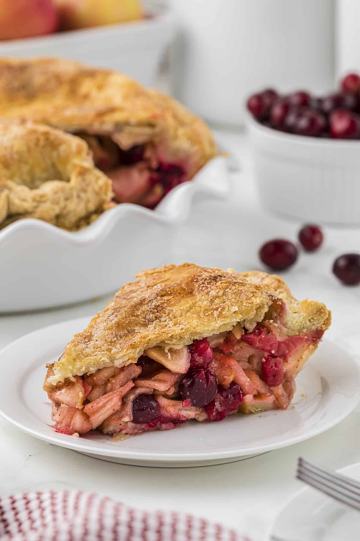 Slice of cranberry apple pie on small dessert plate.