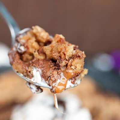 A spoon is held up to the camera with a bite of a skillet cookie on it.
