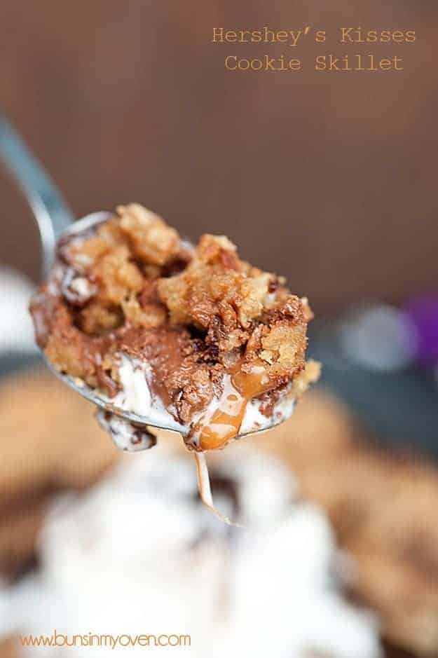 A spoon is held up to the camera with a bite of a skillet cookie on it.