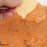A  chip that was dipped in sloppy joe dip being held up to the camera.