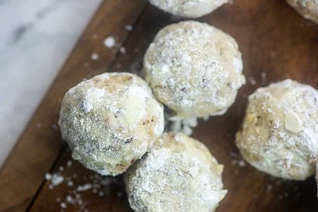 Four pecan cookie balls on a wooden serving dish