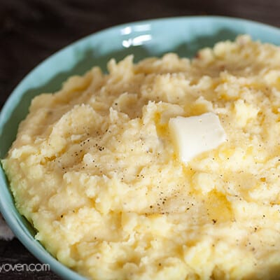 A close up of a bowl of mashed potatoes with melted butter on top.