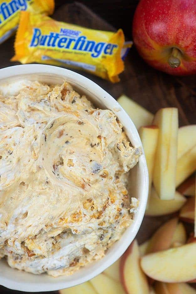 Butterfinger dip in a bowl near sliced apples.