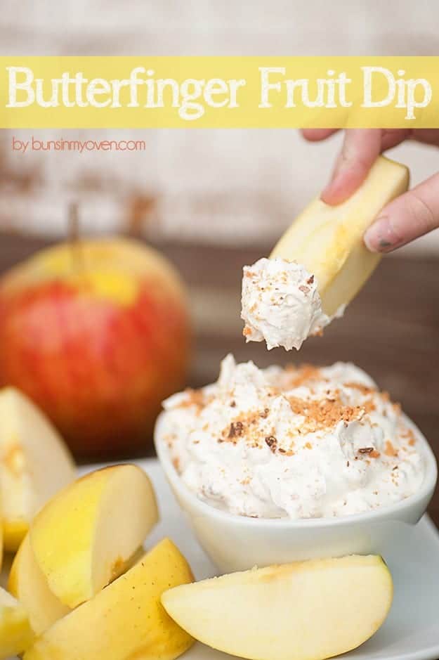 An apple is being dipped into a sauce tray of fruit dip.