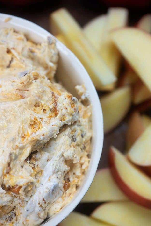 A close up of a bowl of candy bar dip with sliced apples.