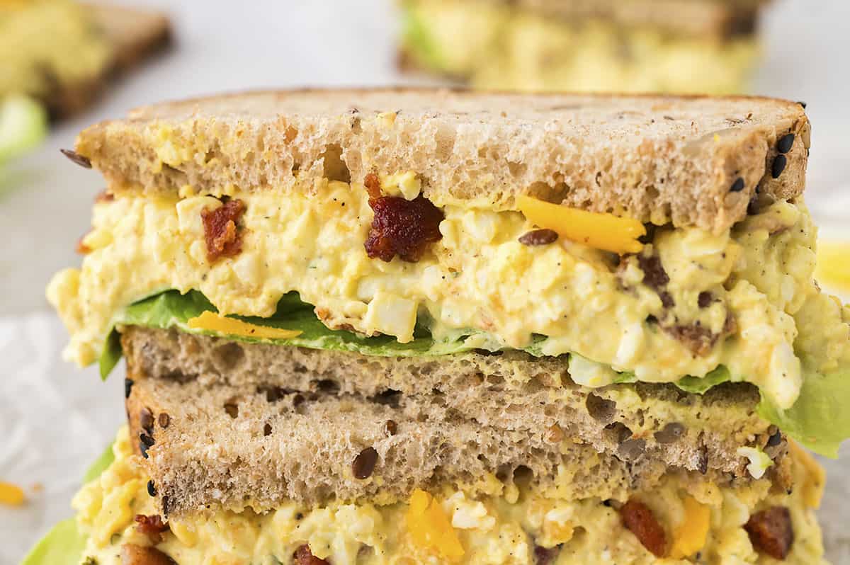 Egg salad sandwich cut in half diagonally and stacked on top of each other.