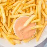 A french fry in a glass jar of fry sauce.