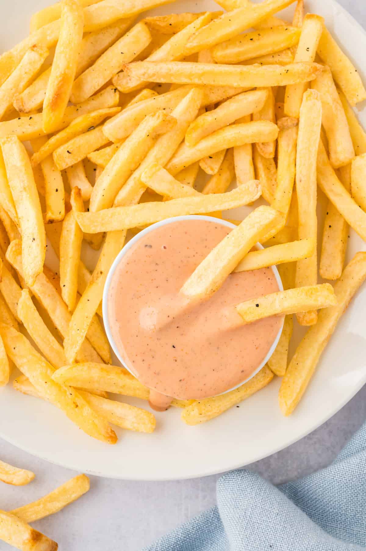 A close up of a french fry in a jar of fry sauce.